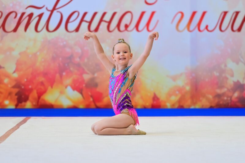 Юная гимнастка улыбается на выступлении